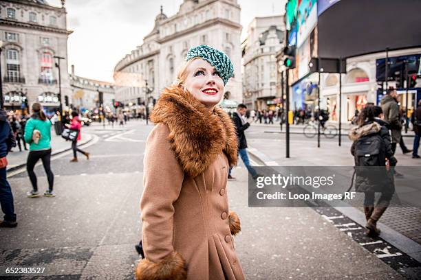 a stylish young woman dressed in 1930s style clothing walking about at piccadilly circus - 1930s woman stock pictures, royalty-free photos & images