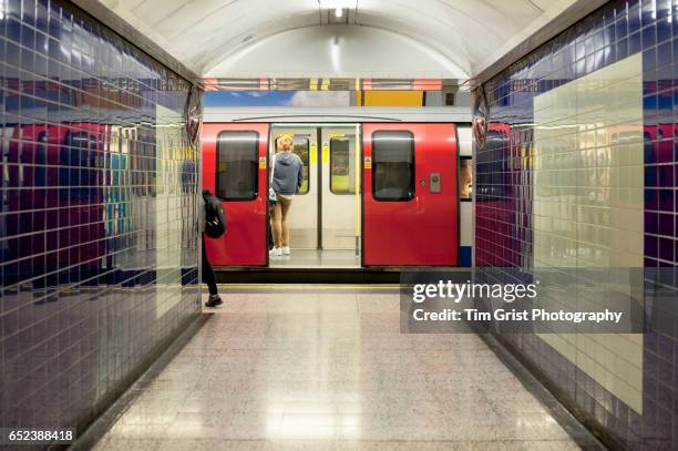 tube train at a station, london - london tube stock-fotos und bilder