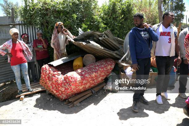 People stand near their damaged houses caused by a landslide, that swept through a massive garbage dump, are seen at Koshe rubbish tip in Kolfe...