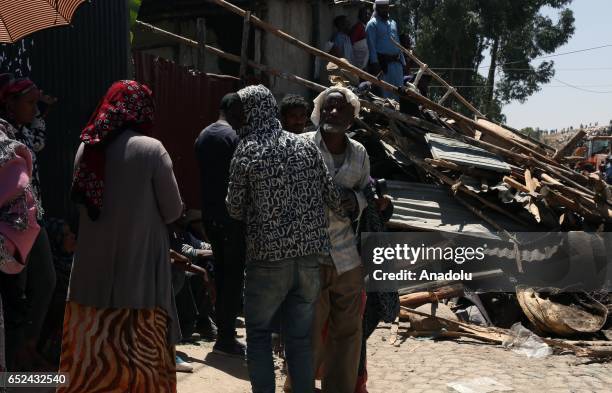 People stand near their damaged houses caused by a landslide, that swept through a massive garbage dump, are seen at Koshe rubbish tip in Kolfe...