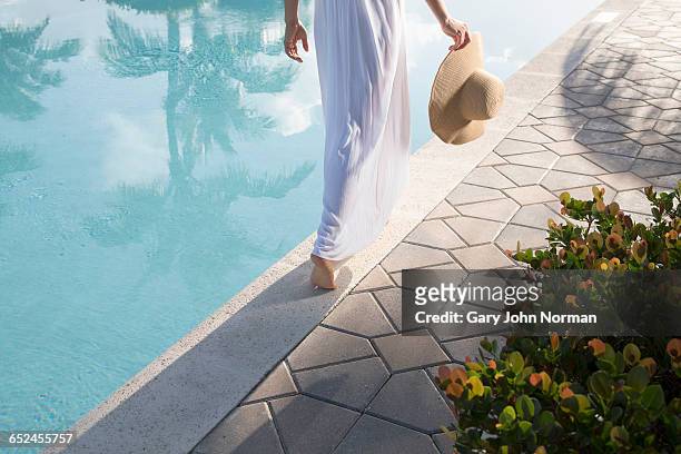 woman in white dress walking close to pool edge - white tiles stock-fotos und bilder