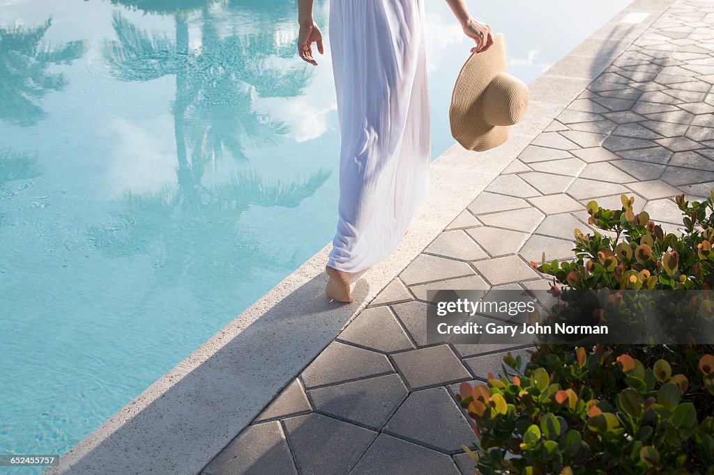 Woman in white dress walking close to pool edge