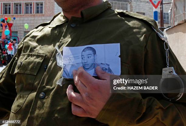 Jewish settler dressed in military fatigues wears a portrait of Elor Azaria, an Israeli soldier who shot dead a wounded Palestinian assailant in...