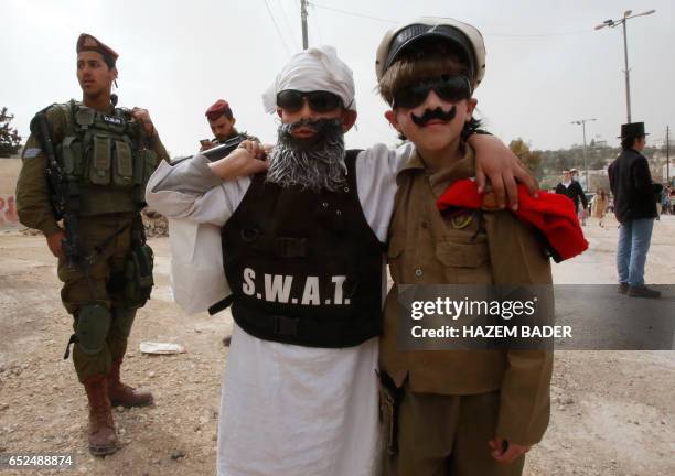Young Israeli settlers wearing costumes pose for a picture during a parade to celebrate the Jewish holiday of Purim in al-Shuhada Street, in the West...
