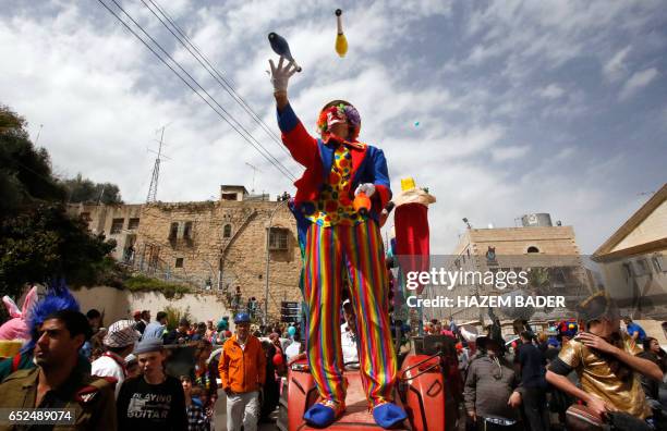 Israeli settlers take part in a parade to celebrate the Jewish holiday of Purim in al-Shuhada Street, in the West Bank town of Hebron, on March 12,...