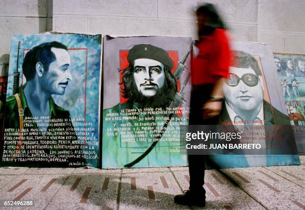 Woman passes in front of the paintings of Ernesto Ché Guevara, Venezuelan guerrilla Brave Douglas and Venezuelan Carlos Ilich Ramirez Sanchez,...