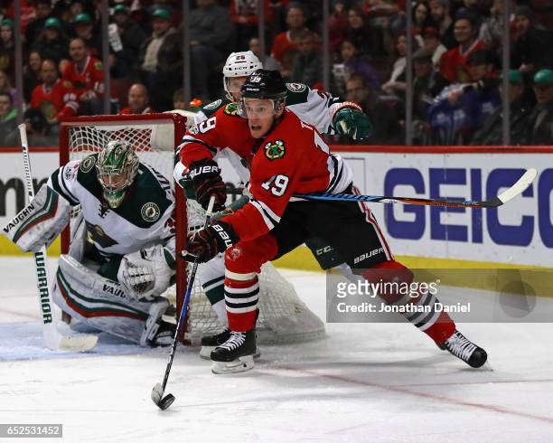 Jonathan Toews of the Chicago Blackhawks is prressured by Jonas Brodin of the Minnesota Wild as he skates around Darcy Kuemper oin the net at the...