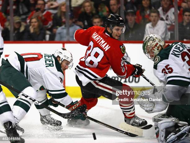 Darcy Kuemper of the Minnesota Wild moves to stop a shot by Ryan Hartman of the Chicago Blackhawks as Jordan Schroeder defends at the United Center...