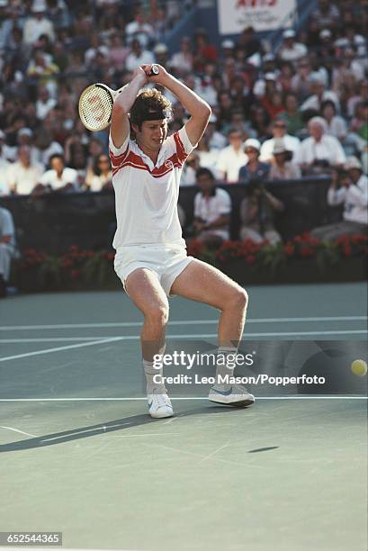 American tennis player John McEnroe raising his tennis racket over his head in anger during competition to progress to win the final of the 1980 US...