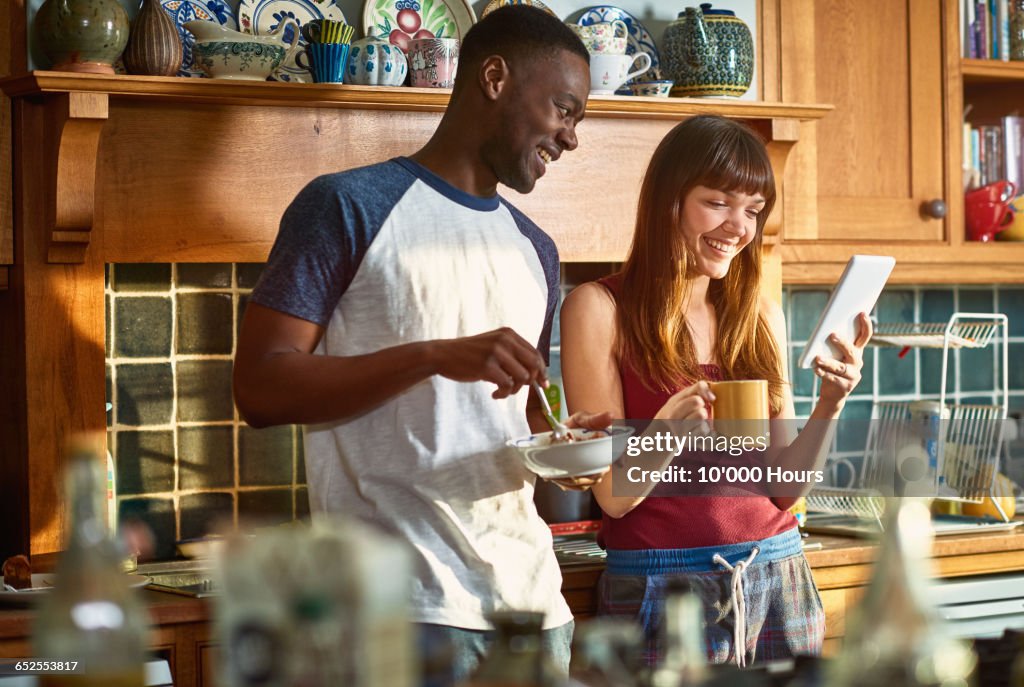 Flatmates laughing at something on digital tablet