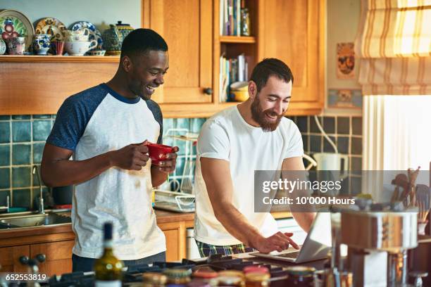 flatmates laughing about something on a laptop - flatmate stock pictures, royalty-free photos & images