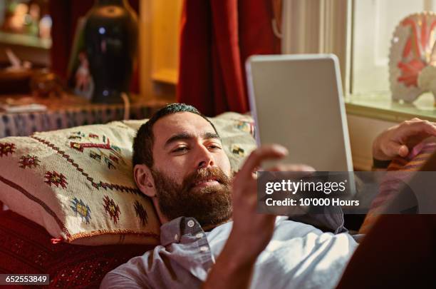 young man relaxing with a digital tablet - livre électronique photos et images de collection