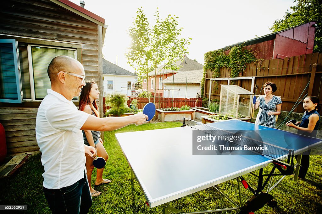 Family playing game of ping pong in backyard