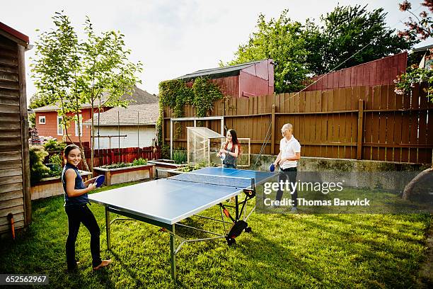 smiling father and daughters playing ping pong - friends table tennis stock pictures, royalty-free photos & images