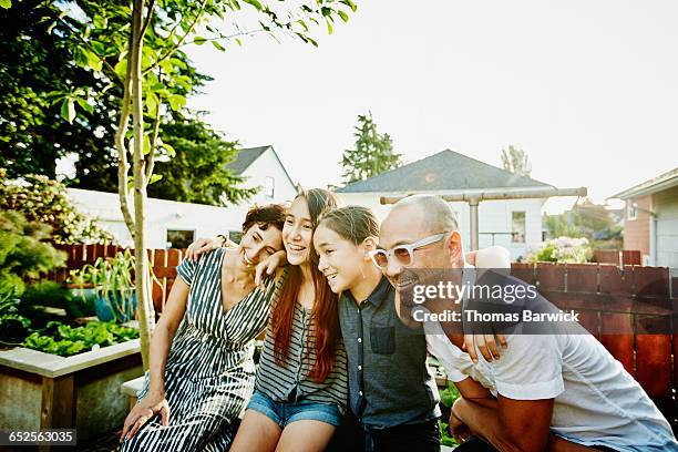 smiling family embracing in backyard of home - idyllic community stock pictures, royalty-free photos & images