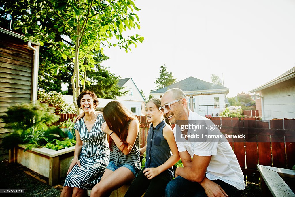 Laughing family sitting together in garden of home