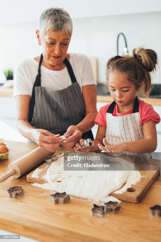 Grandmother teaching her granddaughter to make cookies