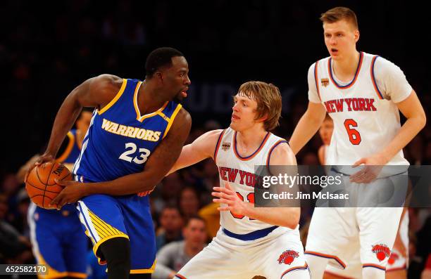 Draymond Green of the Golden State Warriors in action against Ron Baker and Kristaps Porzingis of the New York Knicks at Madison Square Garden on...