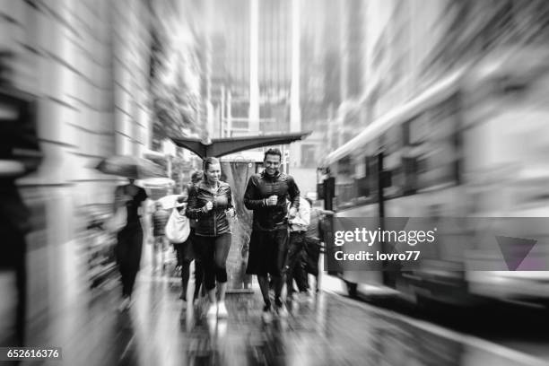 young couple running in the rain at morning through the city streets. - sydney buses stock pictures, royalty-free photos & images