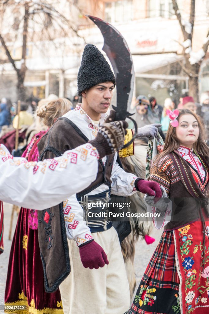 Kukeri And Other Costumed Bulgarians Dancing And Singing During A Traditional Kukeri Festival