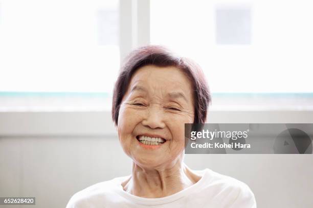 portrait of senior woman in her 80's smiling at home - japanese old man stock-fotos und bilder