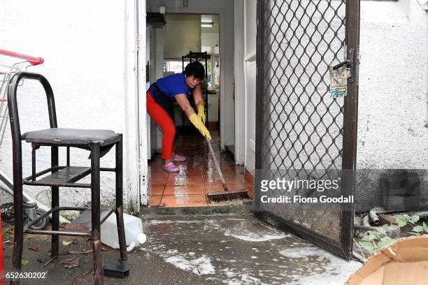 Hui Qui cleans up her takeaway shop after flash flooding in Great North Rd, New Lynn on March 13, 2017 in Auckland, New Zealand. The Tasman tempest...