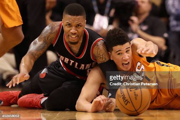 Damian Lillard of the Portland Trail Blazers and Devin Booker of the Phoenix Suns reach for a loose ball during the second half of the NBA game at...