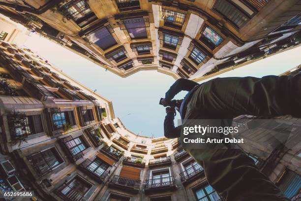 beautiful below view with wide angle lens taken from the ground and looking up of tourist traveler taking pictures and contemplating the beautiful streets of gothic quarter in barcelona city with narrow street and nice round square. - ungewöhnliche perspektive stock-fotos und bilder
