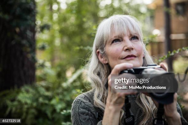 woman taking nature photographs outdoors - senior hobbies stock pictures, royalty-free photos & images