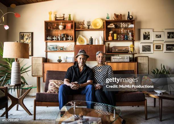 portrait of senior couple (60yrs) sitting on couch at home - man sitting on sofa fotografías e imágenes de stock