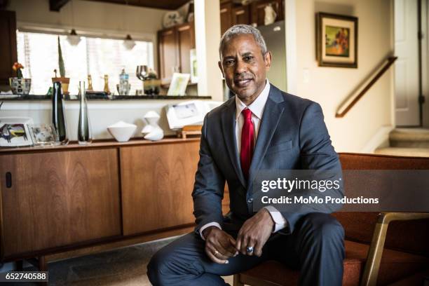 portrait of man (60yrs) sitting on chair at home - african american businessman stock pictures, royalty-free photos & images