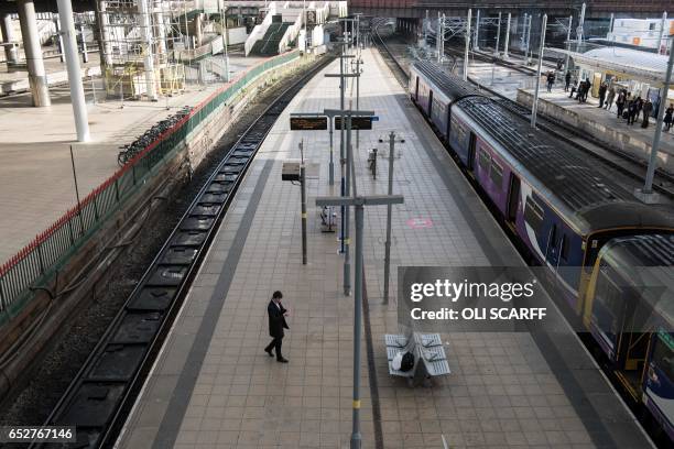 Man waits on a platform in Manchester Victoria train station during a reduced transport service due to industrial action taken by the RMT union in...