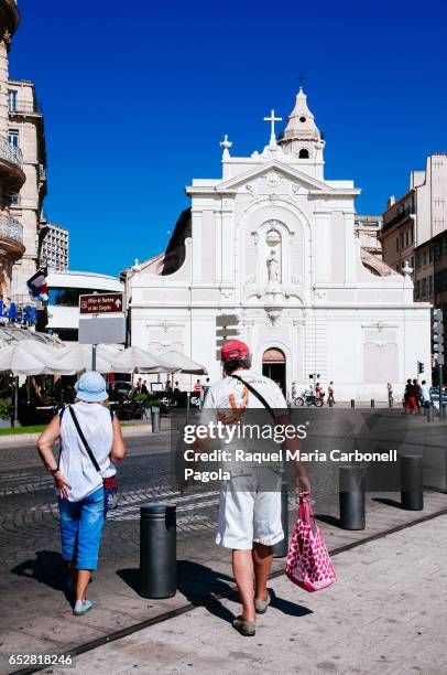 Couple walking on street passing by Church Saint Ferreol Les Augustins in old port.