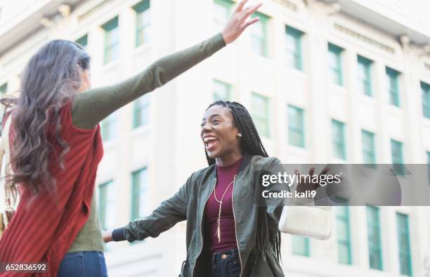 two young women embracing on street corner - open arms hug stock pictures, royalty-free photos & images