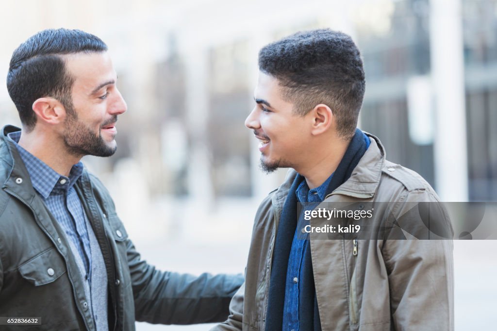 Two young men talking, shaking hands