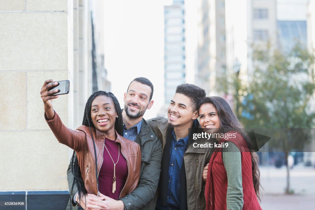 Four young multi-ethnic adults taking selfie in city