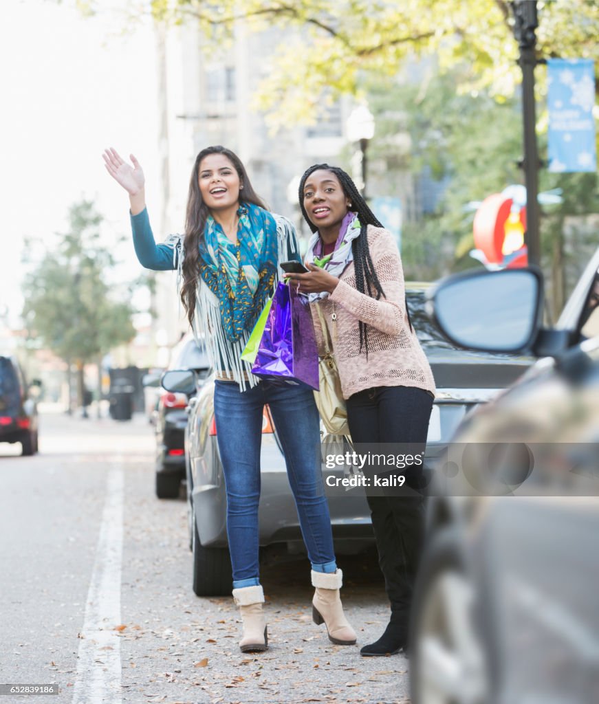 Deux jeunes femmes multiethniques agitant pour taxi