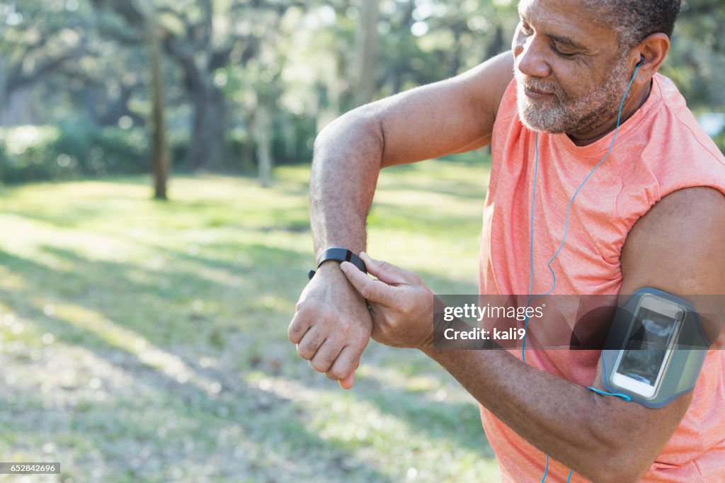 Senior black man with headphones and fitness tracker