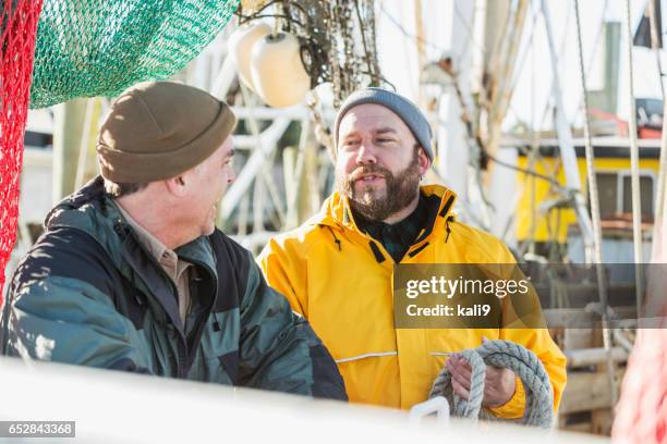 deux hommes mûrs travailler sur bateau de pêche commerciale - pêcheur photos et images de collection