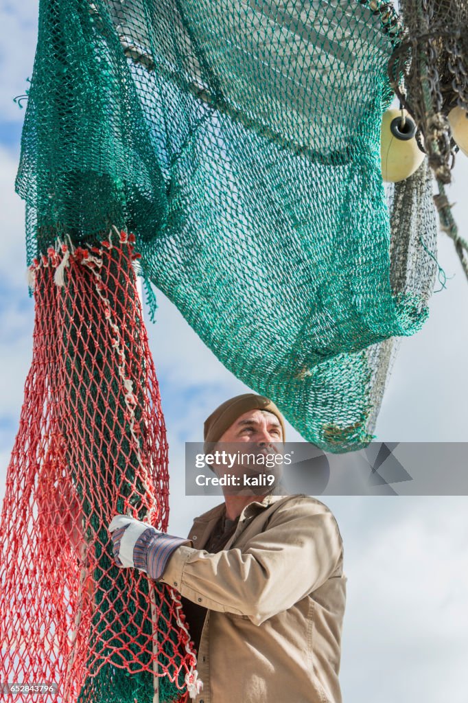 Homme travaillant sur le bateau de pêche commerciale, préparation net
