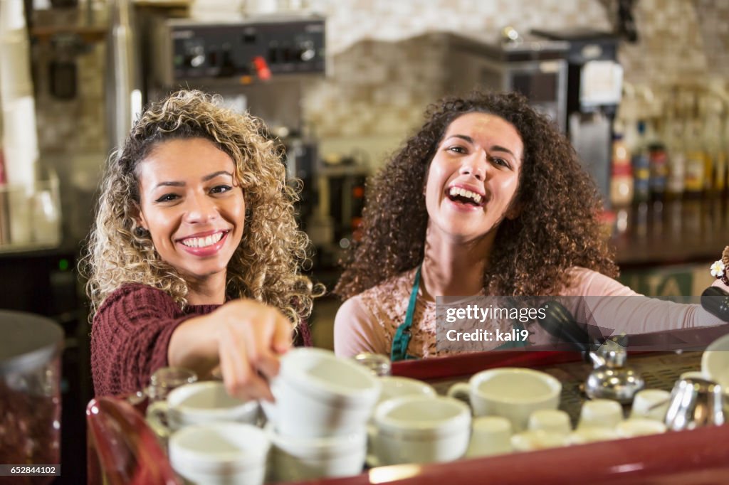 Due giovani donne che lavorano come bariste in una caffetteria