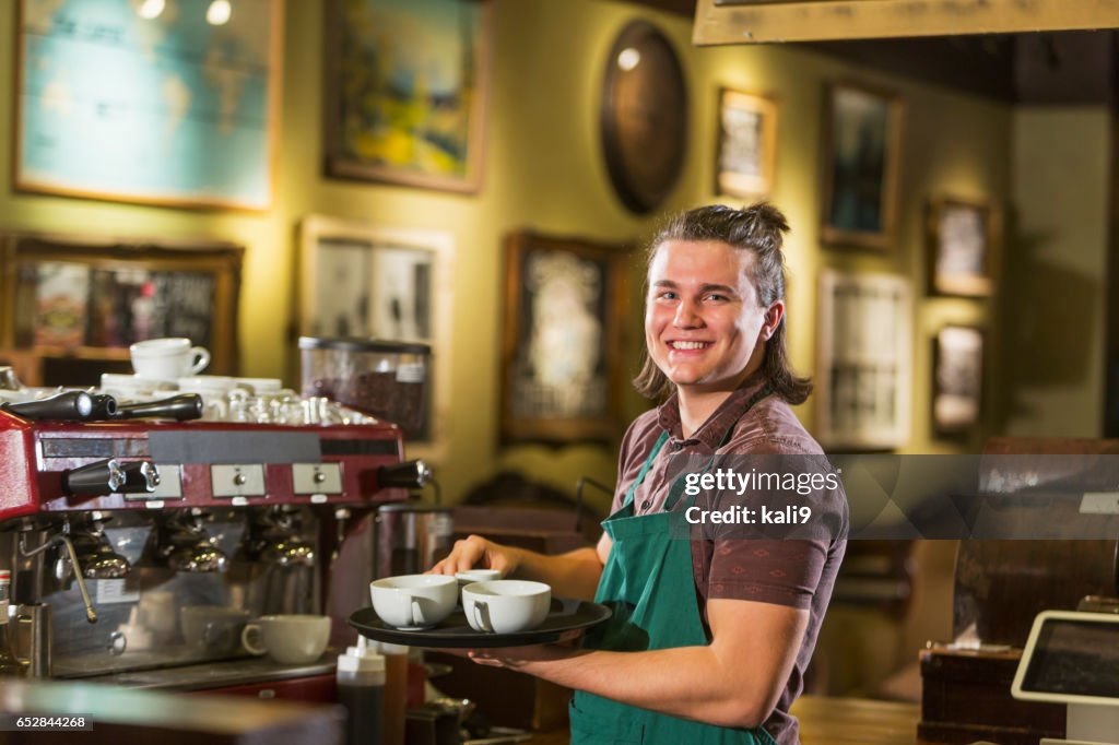 Jonge man met lange haren werken in koffie shop