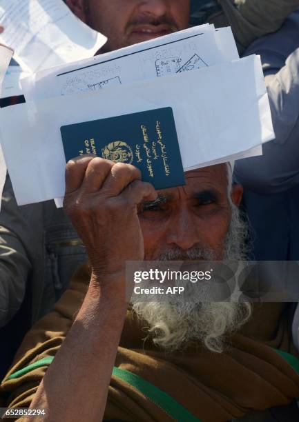 An Afghan national carries his passports as he waits to extend his visa outside the Pakistani immigration office in Peshawar on March 13 following...