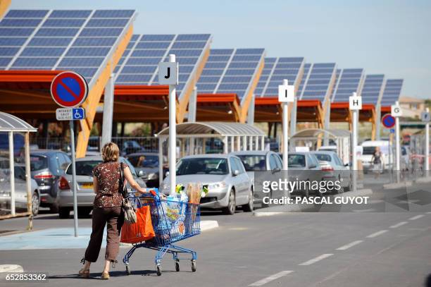 Des clients du centre commercial E.Leclerc de Saint-Aunes passent le 12 juin 2008 sur le parking du supermarché équipé de 12 rangées d'ombrières de...