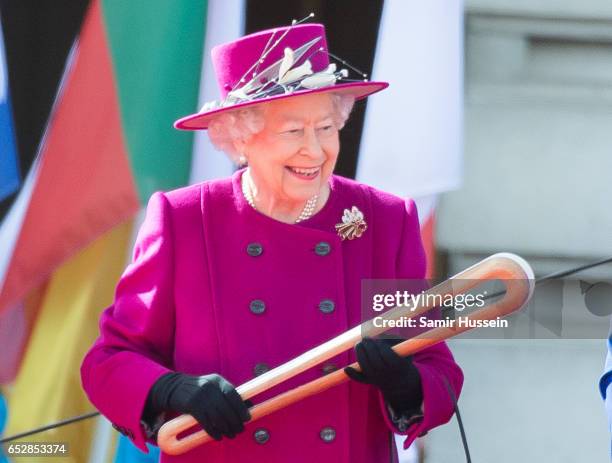 Queen Elizabeth II holds the Commonwealth baton during the launch of The Queen's Baton Relay for the XXI Commonwealth Games being held on the Gold...