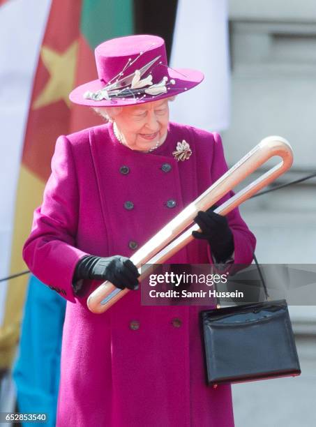 Queen Elizabeth II holds the Commonwealth baton during the launch of The Queen's Baton Relay for the XXI Commonwealth Games being held on the Gold...