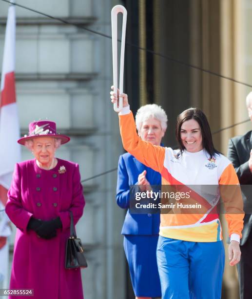 Anna Meares carries the Commonwealth baton as Queen Elizabeth II looks on during the launch of The Queen's Baton Relay for the XXI Commonwealth Games...