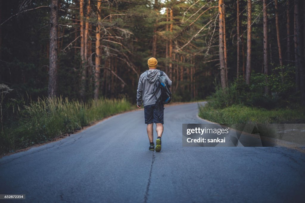 Backpacker wandelingen alleen door de weg in bos