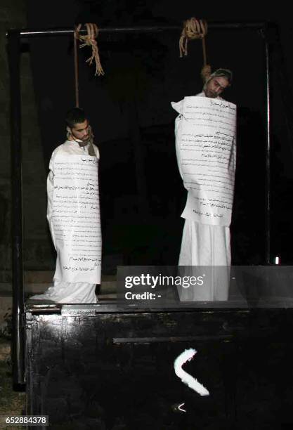 Two executed Syrian men hang from the gallows with a sign detailing their crimes wrapped around their bodies in the centre of the northern town of...