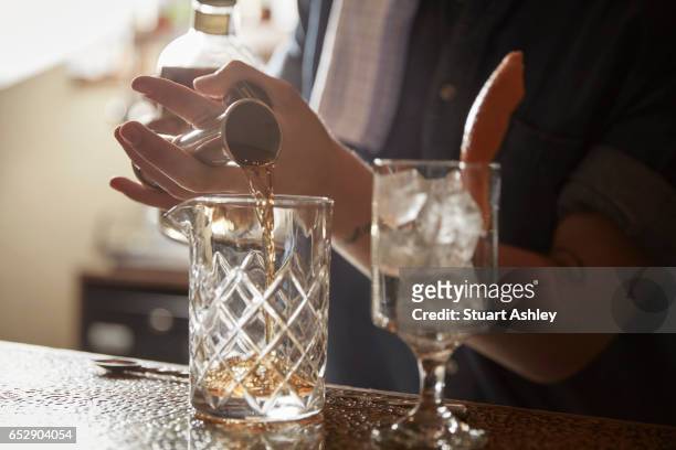 bartender makes old fashion cocktail behind bar - craft cocktail stock pictures, royalty-free photos & images